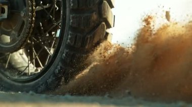 Bir off-road motosikletinin arka tekerini döndürüp havaya çamur atmasının süper yavaş çekimi. Işıklandırma, Hareket ve Patlayıcı Arazi Çarpışması 'na 300 fp kala ele geçirildi. Hız Rampası Efekti