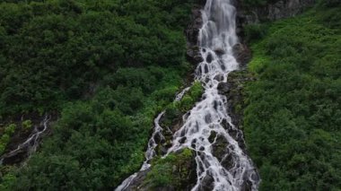 İsviçre Alplerinde eriyen buzullar tarafından beslenen uzun bir orman şelalesinin hava görüntüsü. Yavaş İnsansız Hava Aracı Alp Dağları 'ndan akan Suyun Doğal Güzelliğini Gösteriyor.