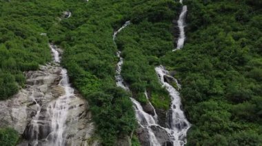 İsviçre Alplerinde eriyen buzullar tarafından beslenen uzun bir orman şelalesinin hava görüntüsü. Yavaş İnsansız Hava Aracı Alp Dağları 'ndan akan Suyun Doğal Güzelliğini Gösteriyor.