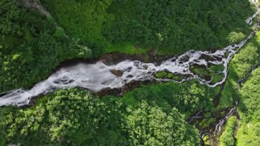 İsviçre Alplerinde eriyen buzullar tarafından beslenen uzun bir orman şelalesinin hava görüntüsü. Yavaş İnsansız Hava Aracı Alp Dağları 'ndan akan Suyun Doğal Güzelliğini Gösteriyor.
