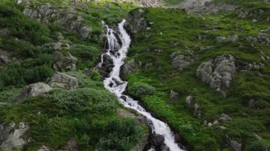 İsviçre Alplerinde eriyen buzullar tarafından beslenen uzun bir orman şelalesinin hava görüntüsü. Yavaş İnsansız Hava Aracı Alp Dağları 'ndan akan Suyun Doğal Güzelliğini Gösteriyor.