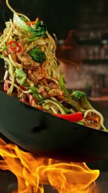 Et ve sebzeli Uçan Asya Yemeklerinin Süper Yavaş Hareketi. High Speed Cinema Camera 'da çekildi, 1000 fps. Arka plandaki Görüntü Mutfağı. Dikey Görünüm Oranı.