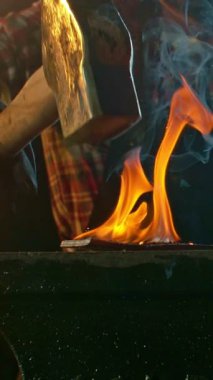 Demircinin sinematik yakın çekimi örsün üzerinde kıvılcımlar uçuşurken kızgın demir dövmesi. Karanlık arka planda dramatik ışıklandırma ile yüksek hızlı kamera ile 300 fp 'de çekildi. Dikey görünüm oranı.