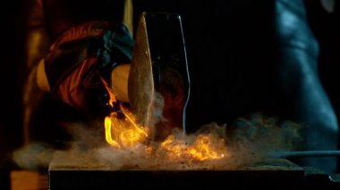 Demircinin sinematik yakın çekimi örsün üzerinde kıvılcımlar uçuşurken kızgın demir dövmesi. Koyu arkaplanda dramatik ışıklandırma ile yüksek hızlı kamera ile 1000 fps hızla çekilmiştir..