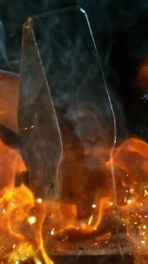 Demircinin sinematik yakın çekimi örsün üzerinde kıvılcımlar uçuşurken kızgın demir dövmesi. Karanlık arka planda dramatik ışıklandırma ile yüksek hızlı kamera ile 300 fp 'de çekildi. Hız rampası etkisi.