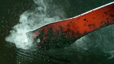 Işıldayan kızgın demirin soğuk suda söndürüldüğü yakın plan. Buhar yükselir, su kabarcıkları ve cızırtılar. Yüksek hızlı kamerayla süper yavaş çekimde çekildi. Metal dövmesi ve soğutma kavramı.