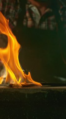 Demircinin sinematik yakın çekimi örsün üzerinde kıvılcımlar uçuşurken kızgın demir dövmesi. Karanlık arka planda dramatik ışıklandırma ile yüksek hızlı kamera ile 300 fp 'de çekildi. Kamera hareket halinde.