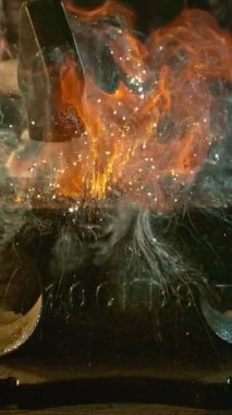 Demircinin sinematik yakın çekimi örsün üzerinde kıvılcımlar uçuşurken kızgın demir dövmesi. Karanlık arka planda dramatik ışıklandırma ile yüksek hızlı kamera ile 300 fp 'de çekildi. Kamera hareket halinde.