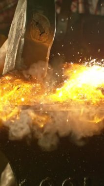 Demircinin sinematik yakın çekimi örsün üzerinde kıvılcımlar uçuşurken kızgın demir dövmesi. Koyu arkaplanda dramatik ışıklandırma ile yüksek hızlı kamera ile 1000 fps hızla çekilmiştir..