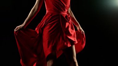 Yakut kırmızısı elbiseli çarpıcı kadın zarif bir şekilde siyah bir arka plana karşı poz veriyor, süper yavaş çekimde yakalandı. Yaklaştır, Ayrıntı.