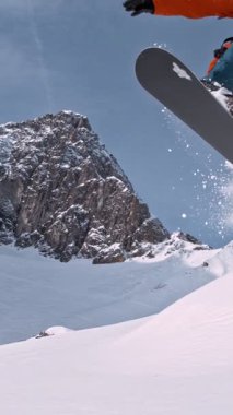 Piste Snowboardcusu atlayışı. Süper Yavaş Hareket, 1000 fp. Avusturya 'nın Avrupa Alp Dağları' nda açık mavi gökyüzü ile güneşli bir günde Piste yamacında snowboard yapmak. Hız Rampası Efekti.