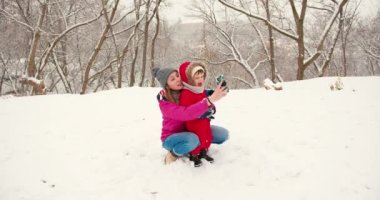 Anne ve küçük çocuk kışın karda eğleniyorlardı. Kış tatili eğlence kızak binme konsepti.