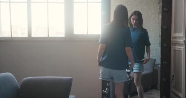 障害のある若い女性は 鏡で人工肢を検査するのに時間がかかります 女性は受け入れと自信を持って義足を見ます — ストック動画