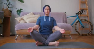 Genç ve iri yarı Latin kız evde yoga yapıyor. Kapalı alandaki bitkilerle iç içe. Çevrimiçi fitness, kentsel orman konsepti.