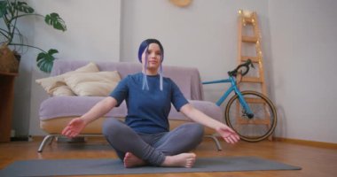 Genç ve iri yarı Latin kız evde yoga yapıyor. Kapalı alandaki bitkilerle iç içe. Çevrimiçi fitness, kentsel orman konsepti.