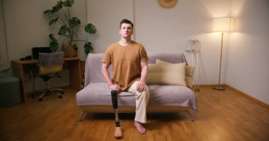 Evinde oturan protez bacak engelli, diz transfemoral bacak protezli insan portresi. Ampütasyon engelli insanlar günlük hayatta.