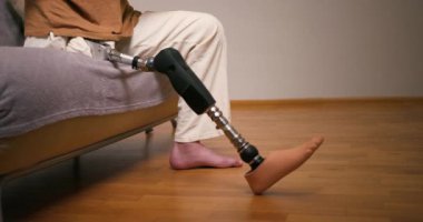 Evinde oturan protez bacak sakatlığı olan bir adamın bacak transfemoral protezini kapat. Ampütasyon engelli insanlar günlük hayatta.