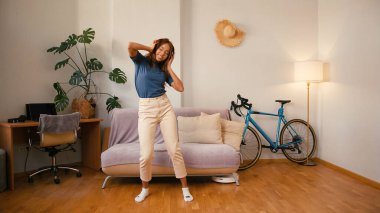 Süpürge süpürgesi dairede yerleri süpürürken Latin kadın dans ediyor. Mutlu İspanyol robotlar evi temizlerken eğleniyor. Karışık ırk toleransı