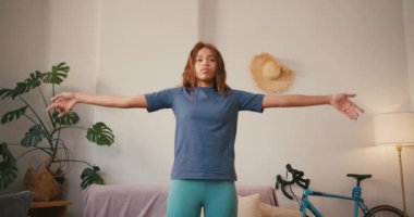 İspanyol kadın evde namaste yoga yapıyor. Gülümseyen Latin bayan oturma odasında farkındalık dengesi kuruyor. Karışık ırk toleransı