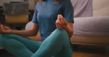 Latin bir kadın Lotus pozu vererek nefes alıp veriyor. Genç İspanyol bayan evde yoga yapıyor. Karışık ırk toleransı