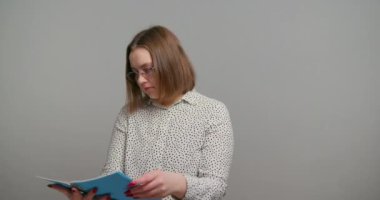Öğretmen her sayfayı yavaş çekimde tarayan kağıt defterleri dikkatlice kontrol eder. Kadının yüzü, güven verici bir jest yaparak aydınlanıyor.