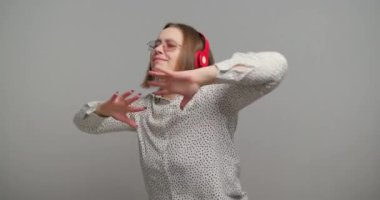 Kulaklıklı mutlu kadın ağır çekimde müziğin ritmiyle dans ediyor. Büyük beden kızlar akıcı ve zarafetle dans eder Melodi ve ritimde kaybolurlar