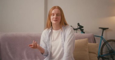 Kızıl saçlı kadın kanepede oturur ve anlamlı jestlerle konuşur. Genç bayan anlamlı gözler ve etkileyici konuşmalar dinleyicileri büyülüyor.