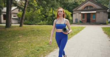 Yürüyen Kendine Güvenen Orta Çağ Spor Giyimli Kadın Yoga minderli Portresi. Güzel bir kadın şehir ortamında eğitime gider..