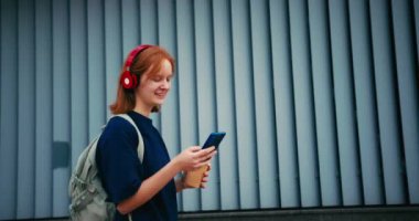 Sırt çantası ve telefonu açık havada olan güzel bir kız öğrenci. Üniversite öğrencisi kampüste yürüyor..