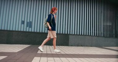 Sırt çantası ve açık havada telefonla dans eden güzel bir kız öğrenci. Üniversite öğrencisi kampüste mutlu..