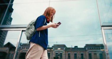 Açık havada kahve ve telefon ile güzel bir genç bayan öğrenci. Üniversite öğrencisi kampüste yürüyor..