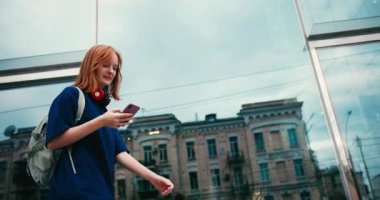 Açık havada kahve ve telefon ile güzel bir genç bayan öğrenci. Üniversite öğrencisi kampüste yürüyor..
