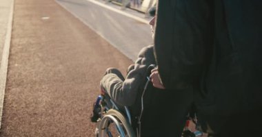 İspanyol adam tekerlekli sandalyedeki engelli arkadaşla ilgileniyor. Arkadaşlar sonbahar parkında birlikte vakit geçiriyorlar. Sağlık sigortası, sakatlık, hareket kabiliyeti, arkadaşlık. 4km 'lik atış..