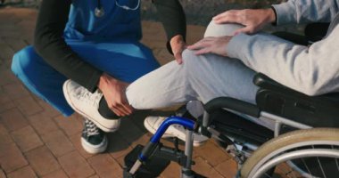 İspanyol doktor tekerlekli sandalyedeki engelli arkadaşla ilgileniyor. Latin sıhhiyeci, yaşlı adama sonbahar parkında rehabilitasyonda yardım ediyor. Sağlık, sakatlık, hareketlilik, arkadaşlık.