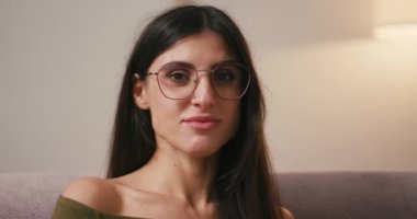 Çıplak omuzlu genç bir kadın, kulağının arkasına saçlarını sıkıştırarak mutluluğunu ifade ediyor. Gevşek saçlı İspanyol kadın, neşeli bir şekilde gülümseyen iltifatlara tepki verir.