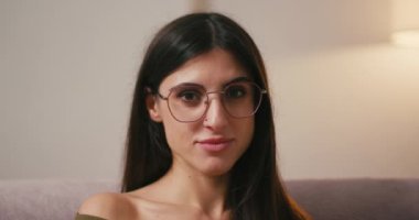 Çıplak omuzlu genç bir kadın, kulağının arkasına saçlarını sıkıştırarak mutluluğunu ifade ediyor. Gevşek saçlı İspanyol kadın, neşeli bir şekilde gülümseyen iltifatlara tepki verir.