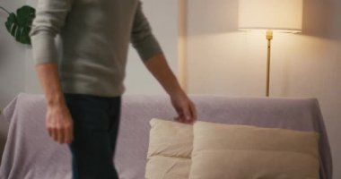 Olgun adam rahat kanepeye oturur ve ellerini başının arkasına koyar. Rahatlamış, gri saçlı, gülümseyen Arap erkeği evdeki oturma odasında dinleniyor.