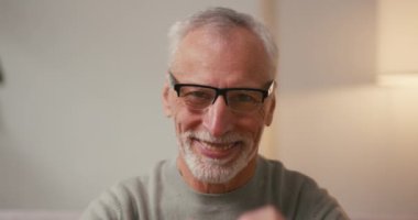 Yaşlı bir Arap evdeki kanepede oturan elleri ile kalp şeklini gösterir. Gri sakallı neşeli olgun erkek, sevgisini ifade eden sevimli hareketler yapar.