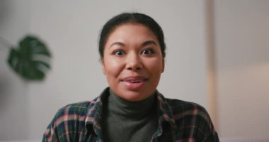 Pozitif İspanyol kadın ev kamerasında görüntülü sohbet yaparken el sallıyor. Bayan blogger oturma odasında sosyal medya için video kaydediyor