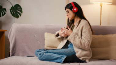 Kulaklıklı genç kadın video konferansına katılıyor. Gevşek saçlı İspanyol kadın evden tabletle online yönetim kurulu toplantısı düzenliyor.