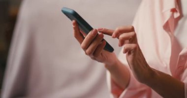 Sosyal medyada akıllı telefonları elinde tutan bir kadın. Kadın, evdeki kanepede oturup internet üzerinden telefon dinleyerek iletişim kuruyor.