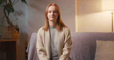 Kızıl saçlı kadın akşam evde komik TV programları seyrederken gülüyor. Neşeli genç bayan işten sonra dinlenmekten zevk alıyor.