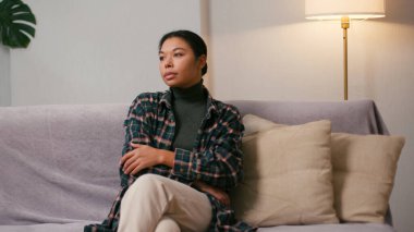 Düşünceli, düşünceli bir İspanyol kadın uzaktan eve bakıyor. Gündelik elbiseli bir kadın gelecek için planlar yapar oturma odasında hayal kurar.