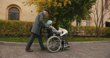 Emekli, haritaya bakan tekerlekli sandalyedeki yaşlı kadına eşlik ediyor. Koca, karısının şehirde doğru yere gelmesine yardımcı olur. Destek ve bakım gösterir.