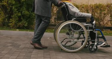 Yaşlı adam, karısını tekerlekli sandalyeyle ara sokaktan geçerken itiyor. Palto giyen yaşlı kadın, eldivenli avuçlarını ovuyor sonbahar parkında eğleniyor.