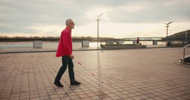 Beyaz bastonlu yaşlı kör adam caddede yürüyor. Engellilik ve şehir keşfi
