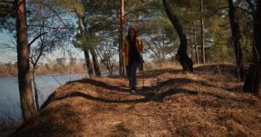 Dağ ormanlarında ağaçların arasında yürüyüş direkleri olan gezgin bir kız. Ormandaki İspanyol ergen.