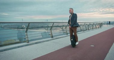 Son sınıf öğrencisi, Electric Mono Wheel Gyro Scooter 'a biniyor. İnsanlar Ekolojik Elektrik Taşımacılık Aracı Kendi Dengeleme Tekerleği.