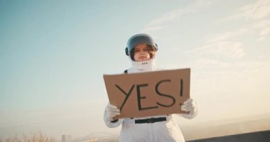 Uzay Elbiseli Kadın Astronot, üzerinde EVET yazan karton bir posterle derin evreni keşfeden İspanyol kadın kozmonot. Siber punk estetiği
