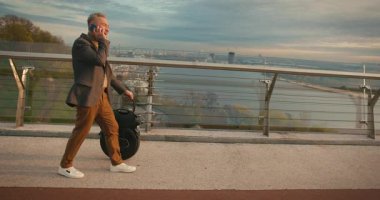 Son sınıf öğrencisi, Electric Mono Wheel Gyro Scooter 'ı tutar. Telefonları kontrol ederken kişisel elektrikli taşıma aracı. İnsanlar Ekolojik Elektrik Taşımacılık Aracı Tekerleği.